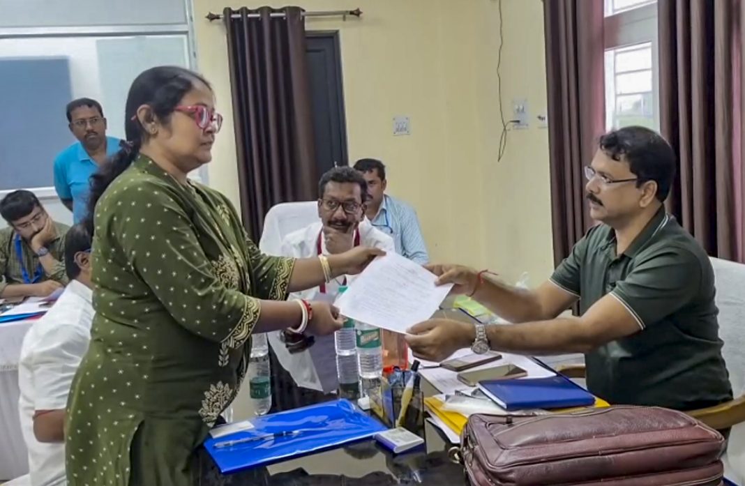 A woman hands a document to an official seated at a desk